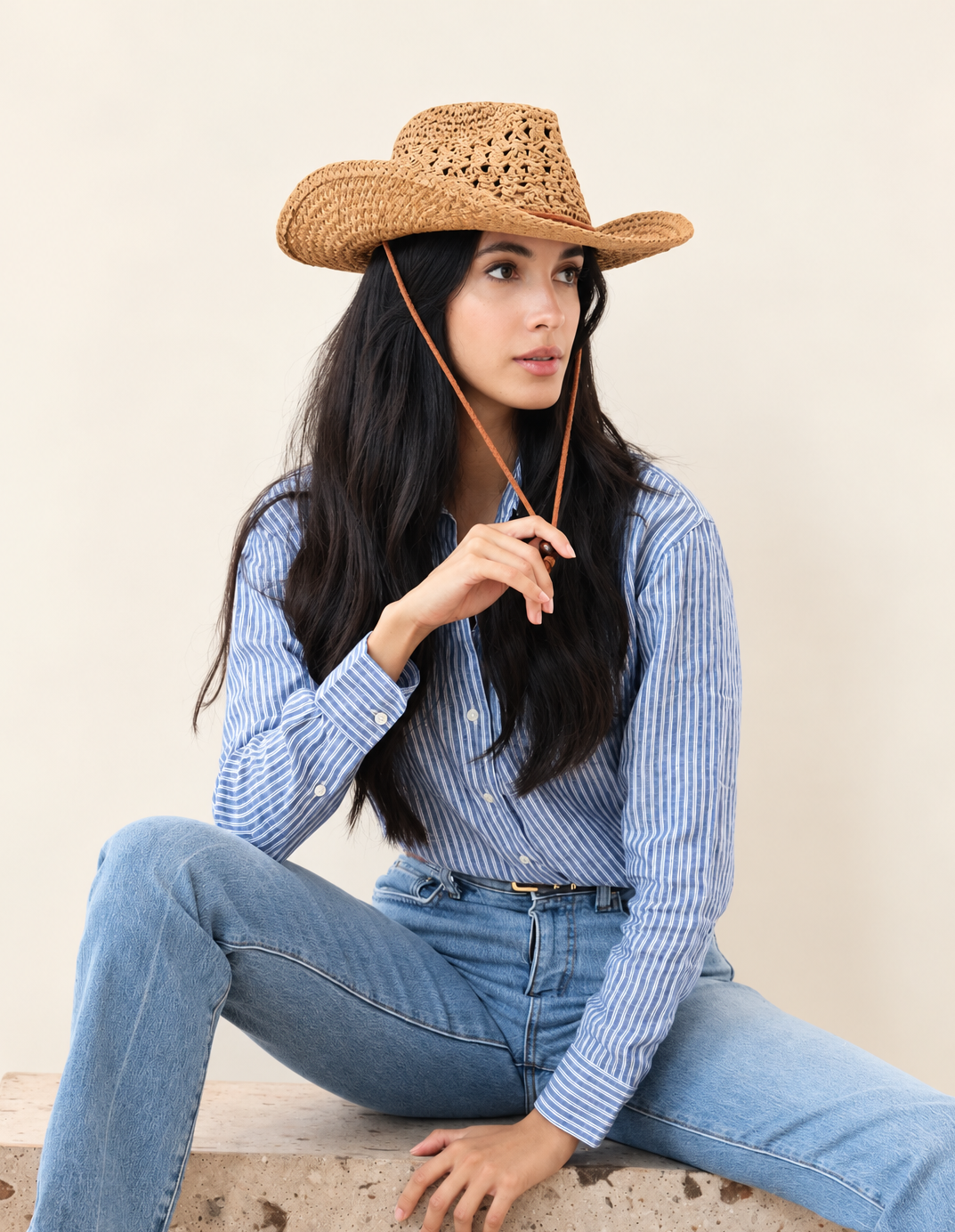 Model wearing Saddle Ridge Straw Cowboy Hat with blue denim outfit while seated