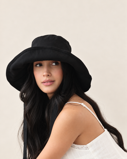 Model wearing Coast Midnight bucket hat with white outfit