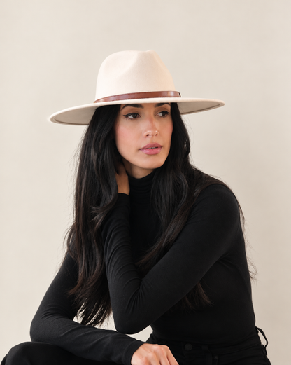 Seated model wearing Birch Aspen wide-brim fedora with black outerwear