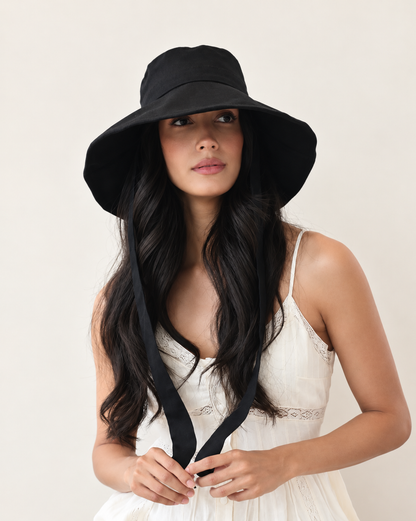 Front view of model wearing Coast Midnight bucket hat with white outfit