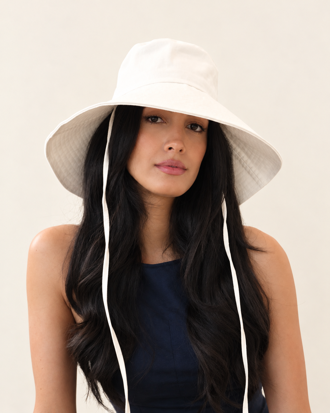 Front view of model wearing Cotton canvas bucket hat with long fabric ties and navy top