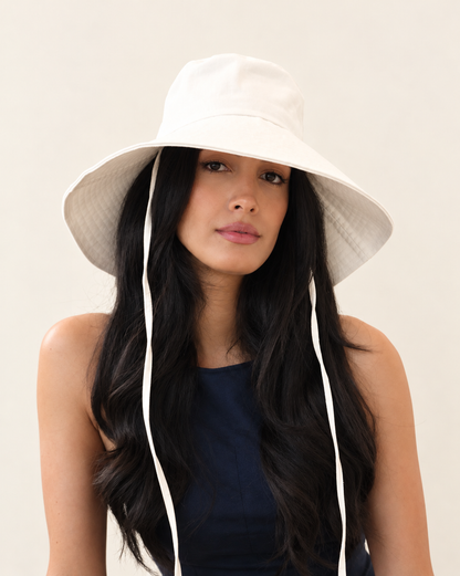 Front view of model wearing Cotton canvas bucket hat with long fabric ties and navy top