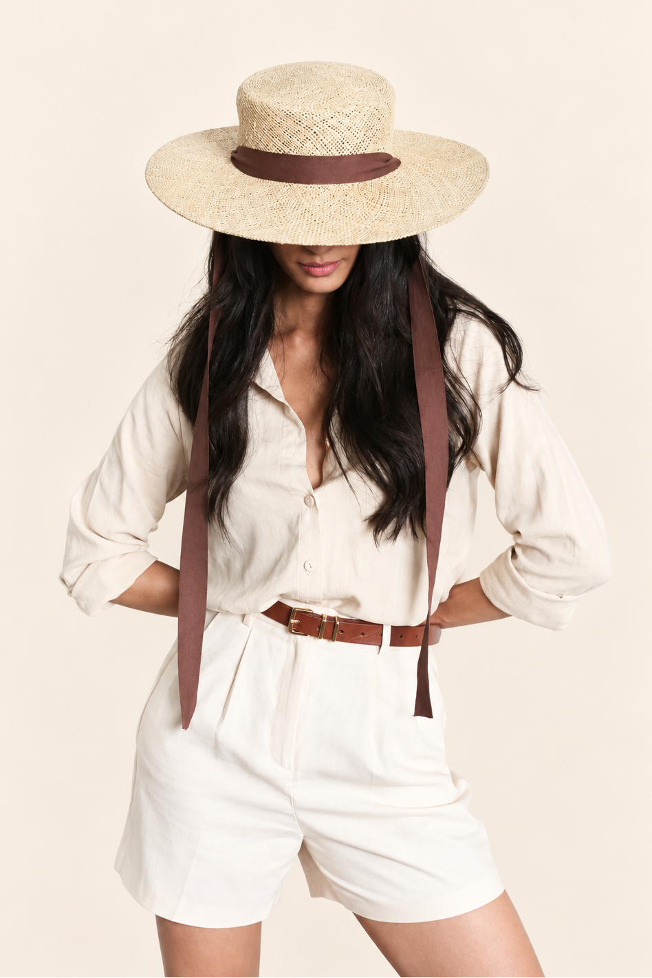 Full outfit view of model wearing natural straw boater hat with brown ribbon and white summer outfit