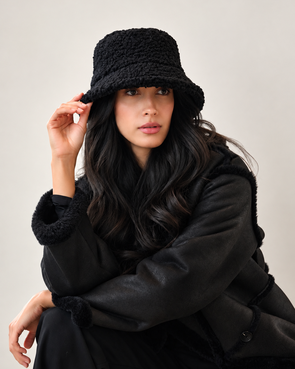 Model wearing shadow black Nube teddy bucket hat with oversized black outerwear