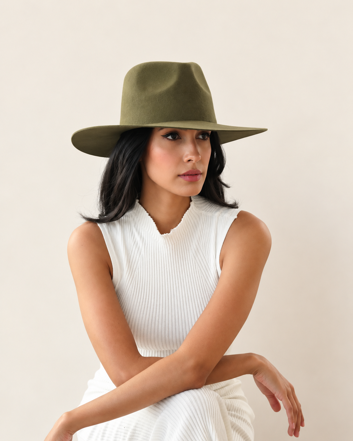 Seated model wearing Sable Wool Fedora Hat in Olive with white outfit