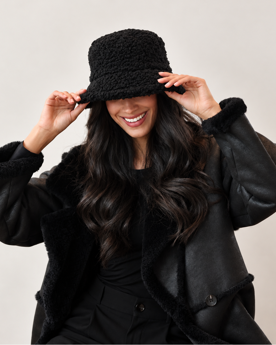 Model adjusting shadow black Nube teddy bucket hat styled with a black jacket