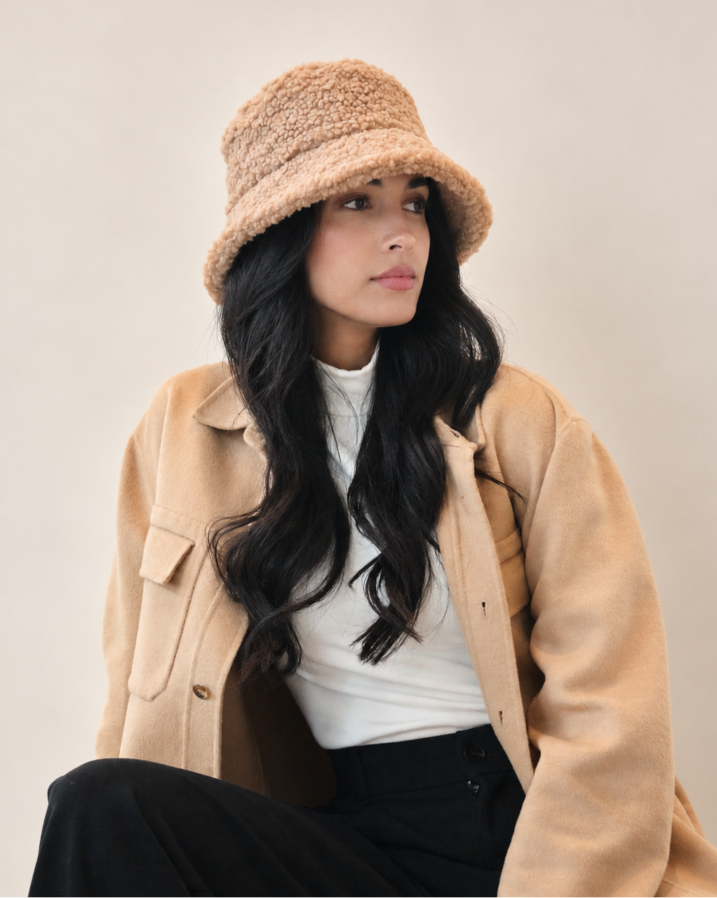 Front view of model wearing brown Nube teddy bucket hat with camel coat