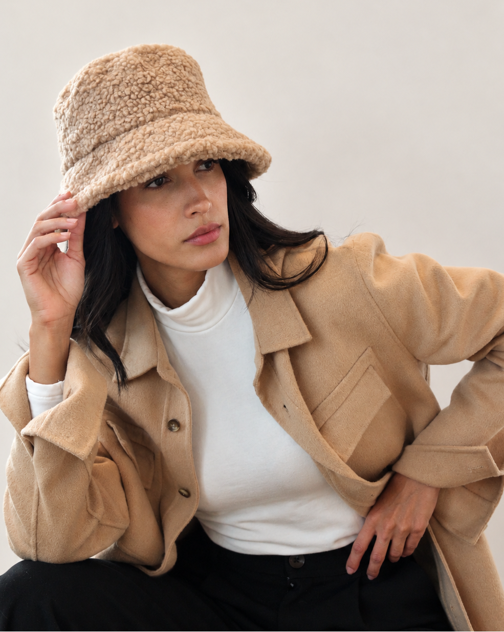 Model adjusting Chestnut Nube teddy bucket hat with camel outerwear